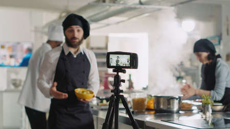 Professional camera recording video of cooking show in restaurant kitchen, people working at chefs...