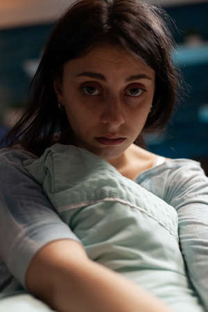 Portrait of anxious adult dealing with sadness and depression, hugging pillow and having suicidal thoughts. Depressed woman in solitude suffering from mental illness and disease. Close up.の写真素材