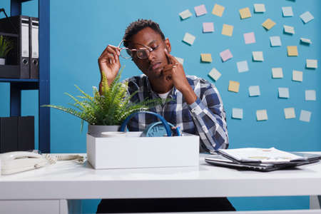 African american young adult left unemployed because of company unsuccessful financial recovery plan. Depressed and upset office worker gathering personal belongings because of job dismissal.の写真素材
