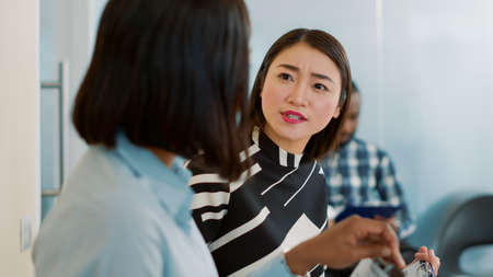 Multiethnic team of women having conversation in waiting lobby at job interview, talking about employment while they sit in queue and wait to start meeting with HR department. Hiring selectionの写真素材