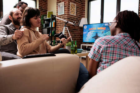 Group of close friends playing space sim videogame on modern gaming console. Young adult people...