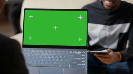 Office worker holding laptop with green screen background, talking to colleague at startup job....