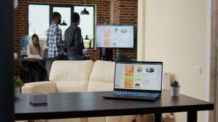 Company office with business charts and graphs on laptop screen, people using profit statistics and...