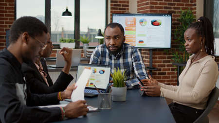 Company employees doing teamwork on financial project, using digital tablet and laptop to analyze...