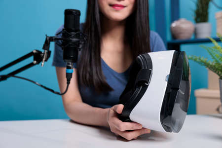 Asian vlogger showing virtual reality goggles at camera advertising production headset equipment in...