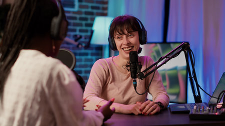 Closeup of online radio host recording interview with african american famous influencer in late night talk show in home studio. Casual woman interviewing content creator using audio equipment.の写真素材