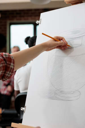 Artist man drawing vase sketch on white canvas working at graphic illustration using sketching technique during art school. Student painter attending creativity lesson for personal growthの写真素材