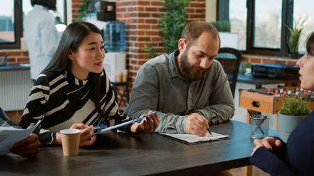 Multiethnic group of workers talking to candidate at recruiting interview, attending professional...