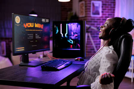 Female player celebrating successful video games online win, using computer to stream gameplay....