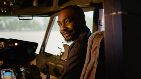 Portrait of african american copilot sitting in airplane cockpit with captain, ready to fly airline plane with control panel dashboard. Navigation command with power engine in cabin.の写真素材
