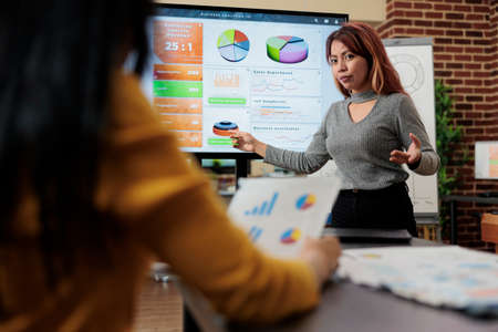 Asian manager discussing management statistics with entrepreneur woman during business meeting in startup office. Businesswomen working at company strategy planning marketing projectの写真素材