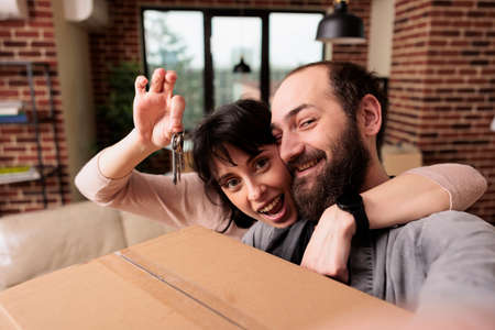 Happy man and woman holding keys of property bought on loan, buying first house together as family....