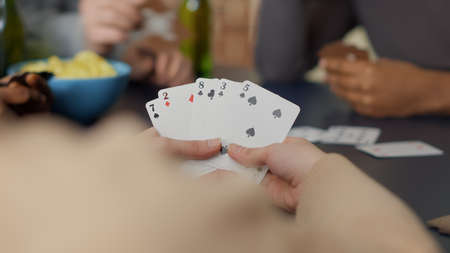Cheerful people enjoying card game with tactics and dice, playing board games together with strategy and cooperation. Young friends having fun with play, drinking beer. Close up.の写真素材