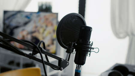 Professional microphone on stand installed in home studio. High tech recording condenser podcast device on empty living room equipped with electronic streaming equipment. Close upの写真素材