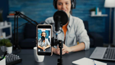 Popular internet star using portable computer while streaming remote podcast show on smartphone....