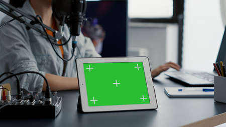 Tablet with chroma key with isolated background and mockup template standing on podcast studio desk....