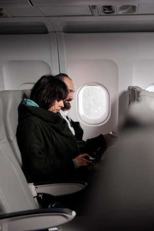 Woman tourist fastening seatbelt before takeoff on airplane flight, buckle up belt to prepare for departure. Flying in economy class and travelling by plane to leave on vacation journey.の写真素材