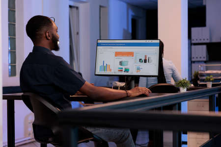 Male company employee analyzing business charts with data on computer screen, using online research...