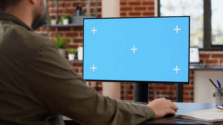 Company manager looking at computer with greenscreen to work on startup business, using blank chroma key display. Working with isolated mockup copyspace on monitor background at desk.の写真素材