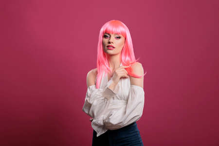 Serious confident woman posing as trendy fashion icon, wearing elegant gamour clothes and having pink hair. Cute attractive girl with sexy makeup look loking at camera, having fun.の写真素材