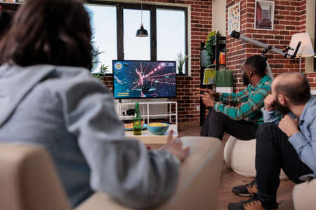 African american man playing video games on tv console, using strategy to play action shooting game...
