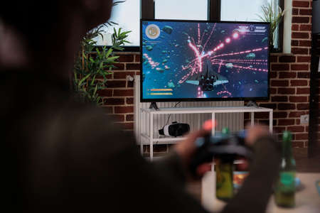 African american woman playing video games with television console, enjoying leisure activity with friends at home. Person having fun with shooting game and competition, tv gaming.の写真素材