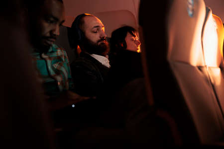 Multiethnic group of people waiting to arrive at destination on economy class international flight. Flying together abroad with airways service and aerial transportation. Airplane jet.の写真素材