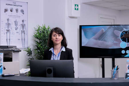 Portrait of smiling front desk receptionist waiting to greet patients in private practice clinic...