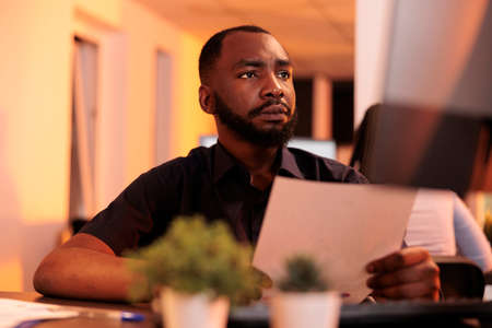 African american freelancer looking at research documents to plan solutions for paperwork report,...