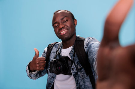 Photography enthusiast giving approve hand gesture while taking picture of himself. Confident...