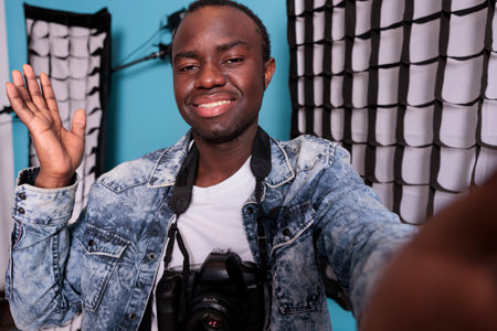 Photography enthusiast taking picture of himself beside softboxes and spotlights. Confident...