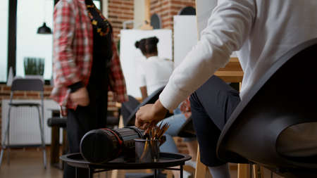 Student using colorful pencils on table to draw sketch in art class. Person taking drawing tools to...