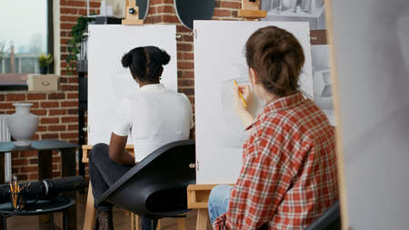 Young woman using pencil to draw vase on white canvas, learning new artistic skills in art class....