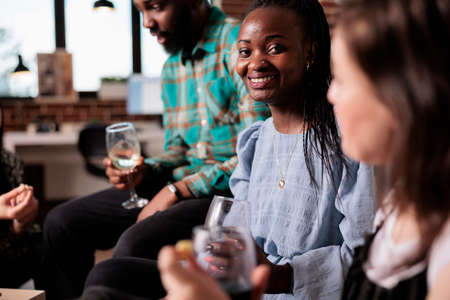 Cheerful woman smiling at camera while attending wine party celebrating best friend birthday. Happy...