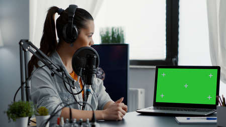 Influencer in studio presenting product on laptop with green screen background. Creative content...