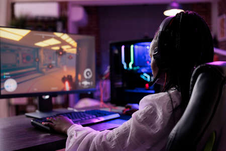 Female streamer having fun with video games online play, playing action game tournament on computer....