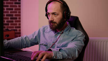 Closeup of man with gaming headset playing multiplayer online action game streaming gameplay on...