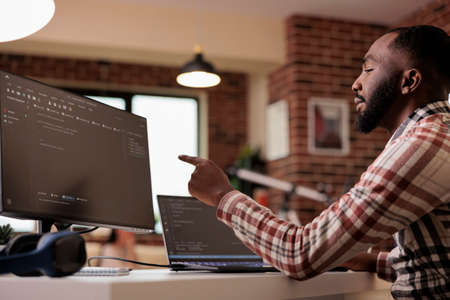 Web developer writing program code and html data base on new user interface. Male freelancer using...