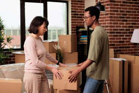 Diverse life partners celebrate moving in together and life event, decorating rented apartment to...