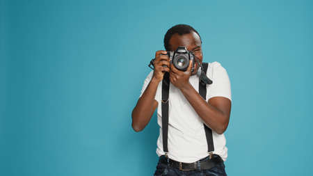 Portrait of male photographer taking pictures with professional camera, using photography equipment to capture creative photos. Focused man shooting with digital lens for production.の写真素材