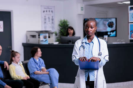 Portrait of confident medic standing in hospital reception waiting for patient appointment for...
