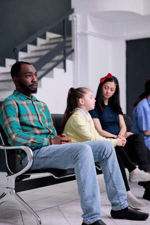 Portrait of african american patient looking tired waiting in busy hospital reception room with...