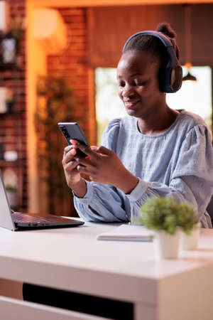 Smiling african american businesswoman typing message on mobile phone. Female freelancer having...