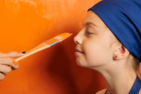 Mother and child playing with orange paint, having fun with messy painting liquid while renovating...