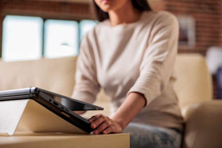 Authentic beautiful good looking asian woman walking with laptop in living room, starting to work...