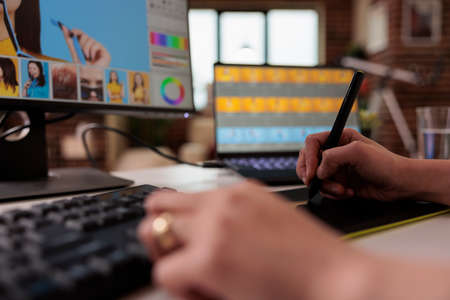 Female editor using stylus on graphic tablet to retouch photo, creating professional photography...