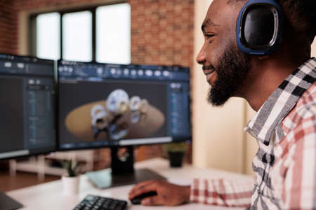 Cad engineer prototyping machinery product on pc, wearing headphones and creating industrial gears model on technical software. Developing machine engine graphics and 3d manufacture.の写真素材