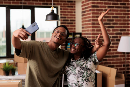 Positive husband and wife taking pictures and recording video in new house, filming apartment relocation after moving in. Using smartphone app to capture life event and home property.の写真素材