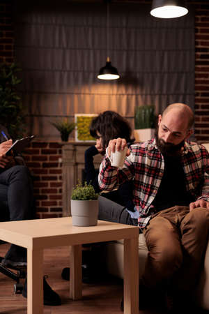 Partners sitting back to back fighting at couple therapy session with counselor, trying to solve...