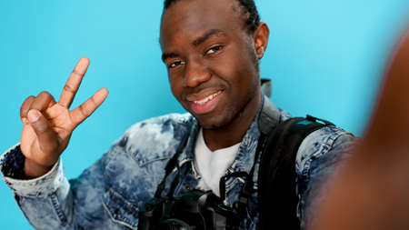 Photographer taking selfies and fooling around in front of camera, doing peace sign and showing okay gesture. Male model having fun with poses, taking photos with professional equipment.の写真素材